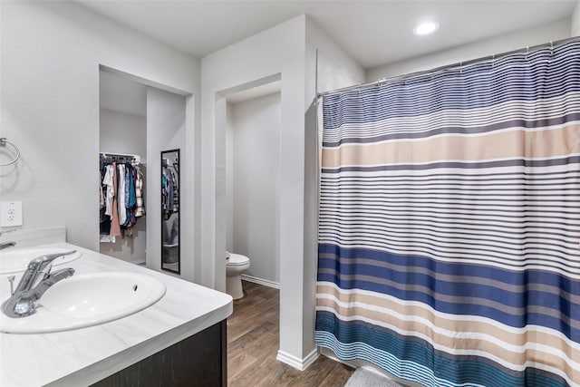 full bath featuring double vanity, wood finished floors, a sink, and toilet