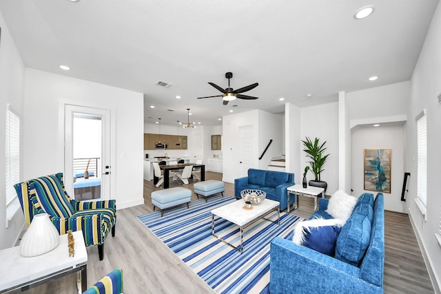 living area with stairs, light wood finished floors, visible vents, and recessed lighting