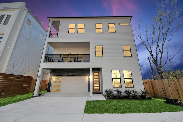 contemporary home with a lawn, fence, a balcony, a garage, and driveway