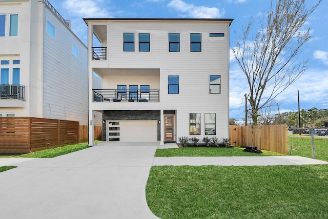 modern home featuring a front yard, concrete driveway, fence, and a balcony