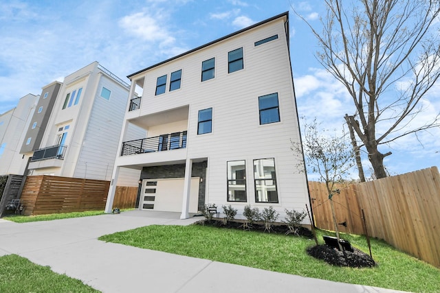 view of front of property with an attached garage, driveway, a front yard, and fence