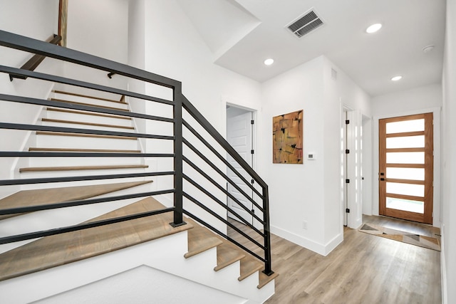 foyer featuring light wood finished floors, stairs, visible vents, and recessed lighting