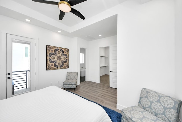 bedroom featuring ceiling fan, recessed lighting, wood finished floors, baseboards, and a tray ceiling