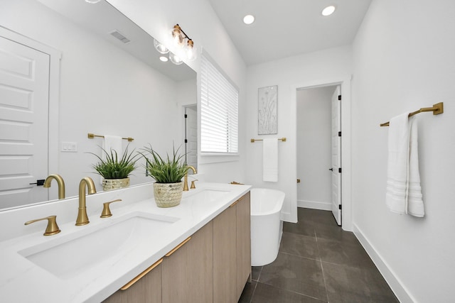 full bathroom featuring a freestanding tub, a sink, baseboards, and tile patterned floors