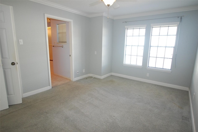 carpeted spare room with ceiling fan, ornamental molding, and baseboards