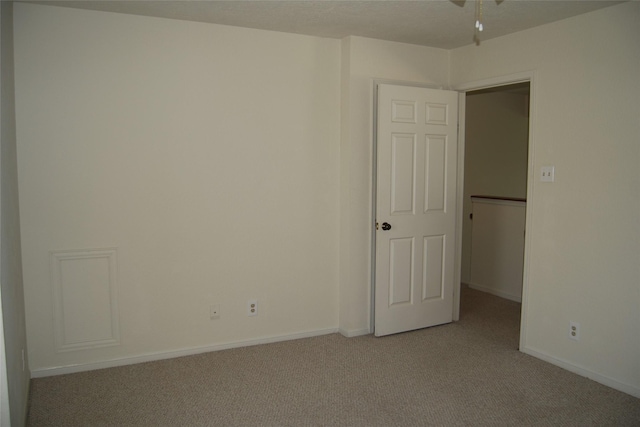 empty room featuring light colored carpet and baseboards