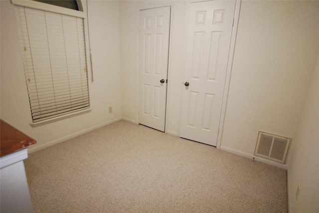 unfurnished bedroom with light carpet, visible vents, and baseboards