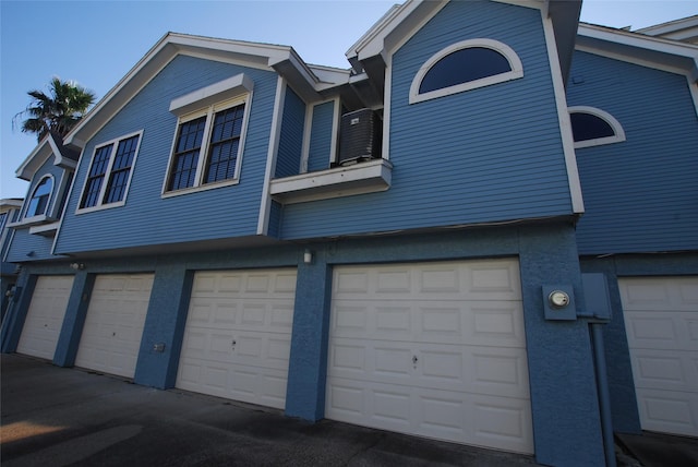 exterior space with cooling unit and an attached garage