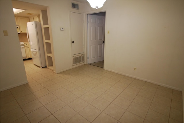 unfurnished room featuring baseboards, visible vents, and light tile patterned flooring