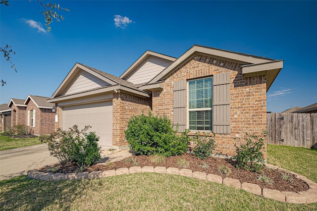 view of front of house with an attached garage, fence, concrete driveway, and brick siding