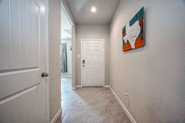 doorway with light tile patterned floors and baseboards