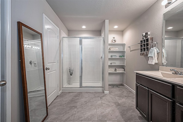 bathroom featuring a stall shower, baseboards, a textured ceiling, vanity, and recessed lighting