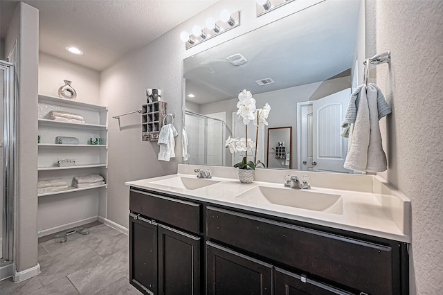 bathroom with a stall shower, visible vents, a sink, and double vanity