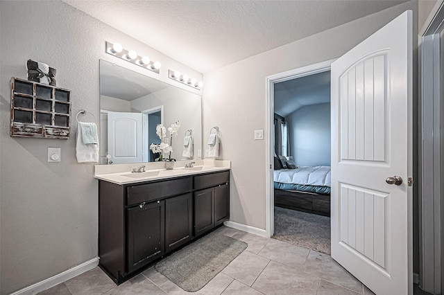 ensuite bathroom featuring baseboards, a sink, ensuite bath, and double vanity