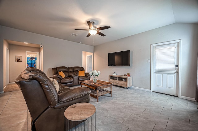 living area with light tile patterned floors, visible vents, vaulted ceiling, ceiling fan, and baseboards