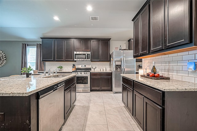 kitchen featuring light tile patterned floors, visible vents, light stone counters, stainless steel appliances, and a sink