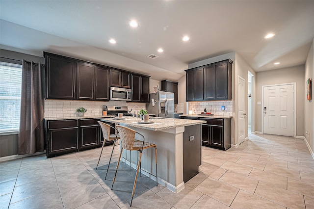 kitchen featuring appliances with stainless steel finishes, visible vents, an island with sink, and light tile patterned floors