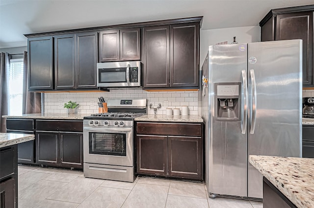 kitchen featuring appliances with stainless steel finishes, light stone counters, and decorative backsplash