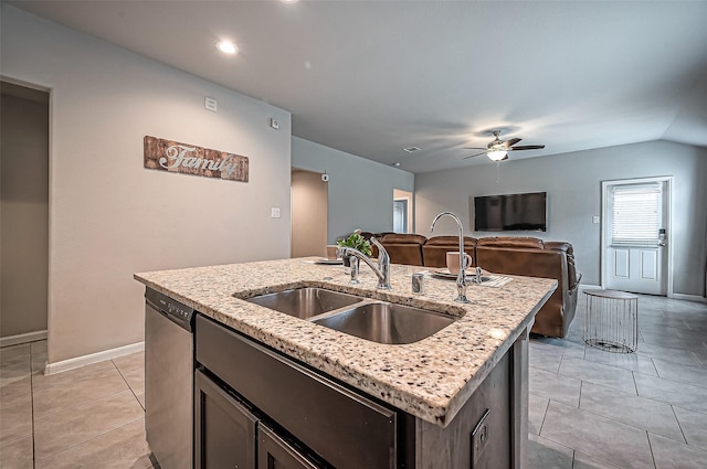 kitchen with light tile patterned floors, light stone counters, a sink, dishwasher, and a center island with sink