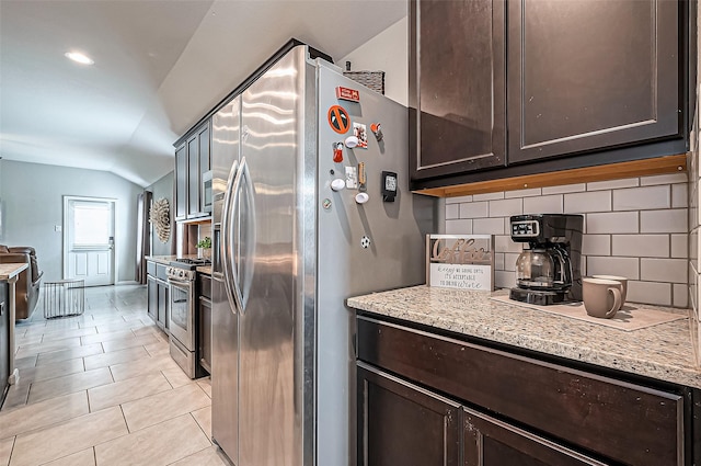 kitchen featuring light tile patterned floors, light stone countertops, vaulted ceiling, stainless steel appliances, and dark brown cabinets