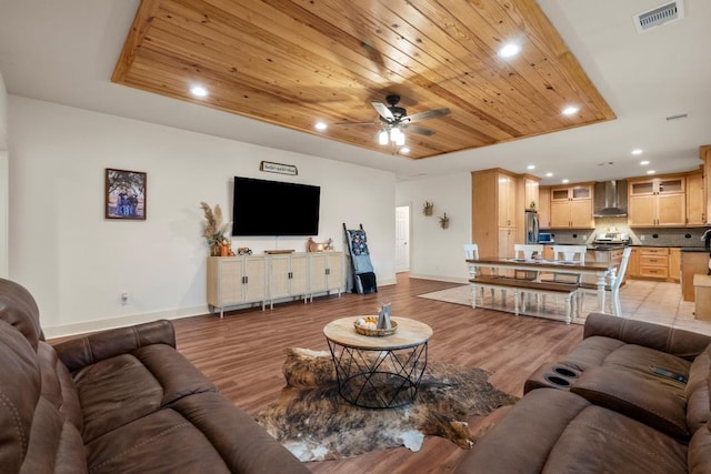 living area with light wood-type flooring, wood ceiling, visible vents, and a tray ceiling