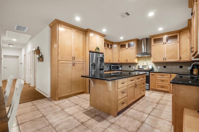 kitchen featuring a kitchen island, visible vents, appliances with stainless steel finishes, wall chimney exhaust hood, and tasteful backsplash