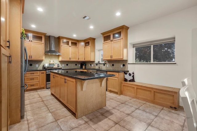 kitchen featuring visible vents, decorative backsplash, a center island, stainless steel appliances, and wall chimney range hood