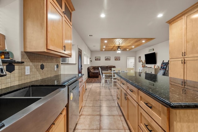 kitchen featuring stainless steel dishwasher, dark stone countertops, open floor plan, and decorative backsplash