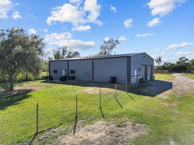 back of house featuring an outbuilding, a garage, an outdoor structure, driveway, and a lawn