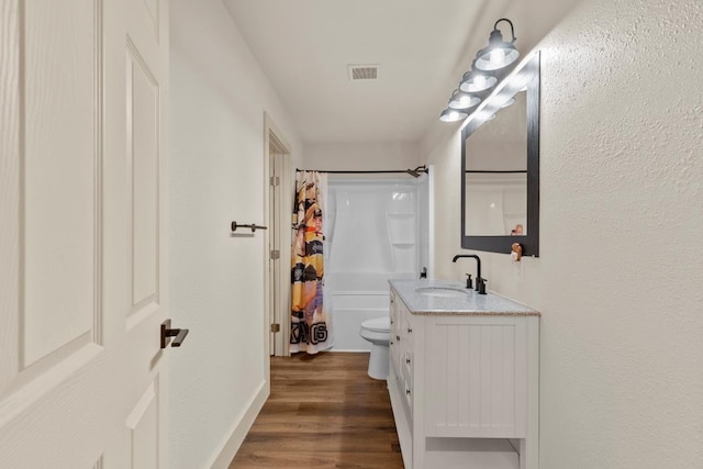 bathroom with shower / tub combo, visible vents, toilet, wood finished floors, and vanity