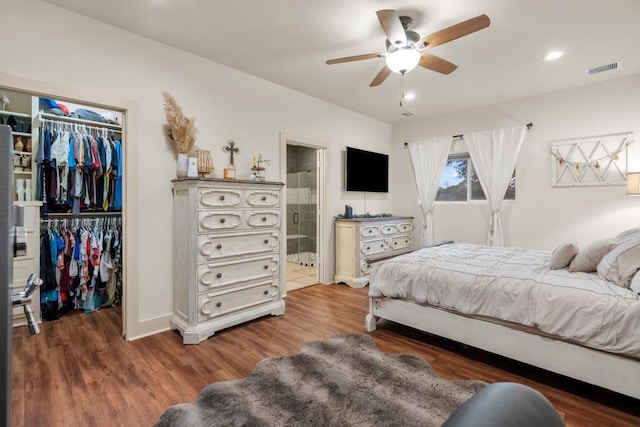 bedroom with a walk in closet, recessed lighting, a closet, visible vents, and wood finished floors