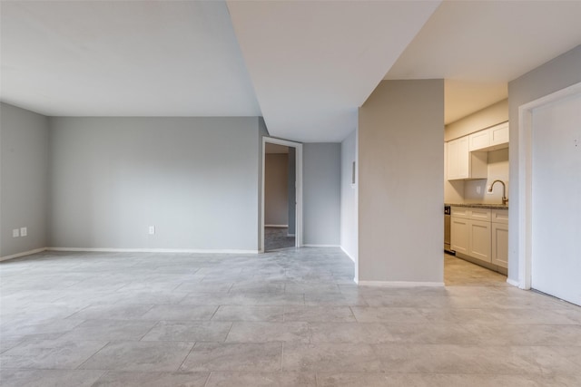 unfurnished living room with a sink and baseboards