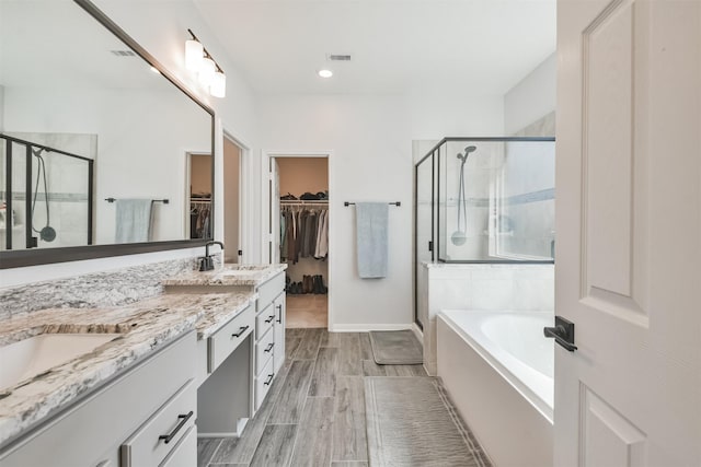 bathroom with a spacious closet, a sink, visible vents, and a shower stall