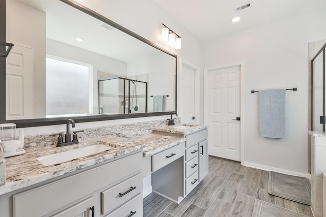 bathroom with a stall shower, visible vents, a sink, and double vanity