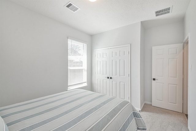 bedroom featuring a closet, visible vents, light carpet, and baseboards