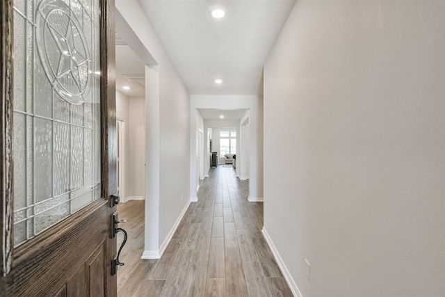 hallway featuring recessed lighting, light wood-style flooring, and baseboards