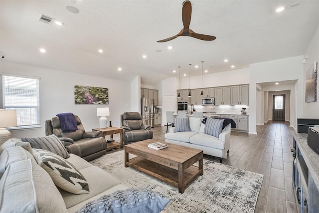 living room featuring light wood-style floors, visible vents, a ceiling fan, and recessed lighting