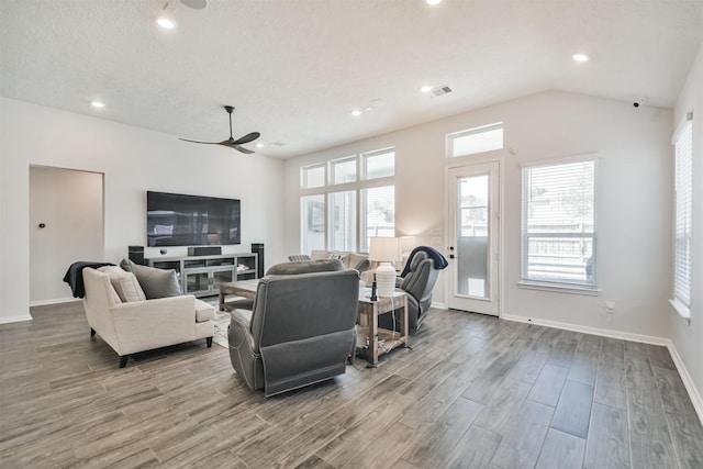 living room with lofted ceiling, wood finished floors, visible vents, and baseboards