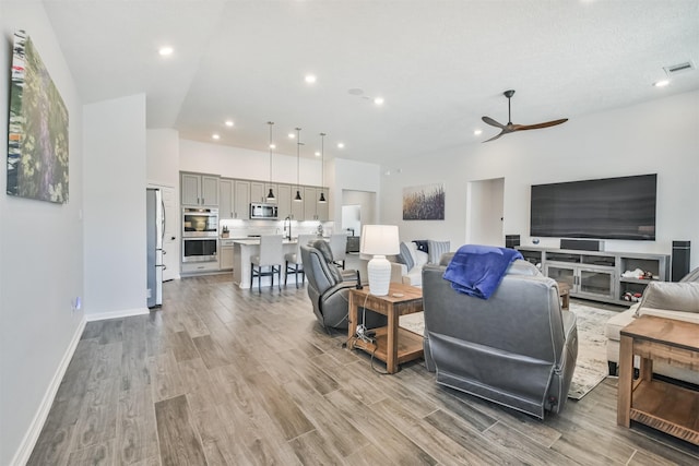 living room featuring ceiling fan, light wood-style flooring, recessed lighting, visible vents, and baseboards