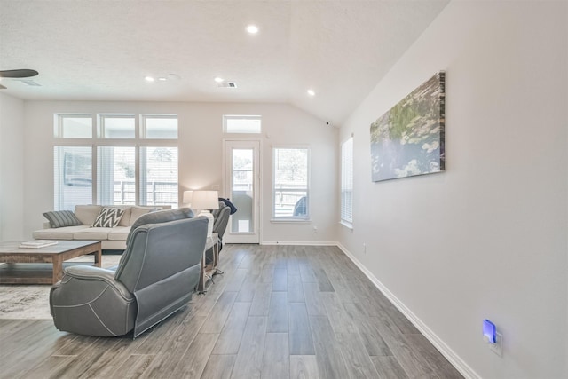 living area with lofted ceiling, baseboards, visible vents, and wood finished floors