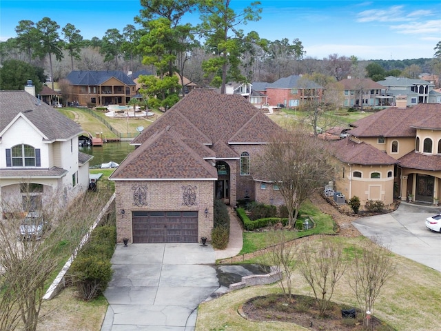 view of front facade featuring a garage, driveway, brick siding, and a residential view