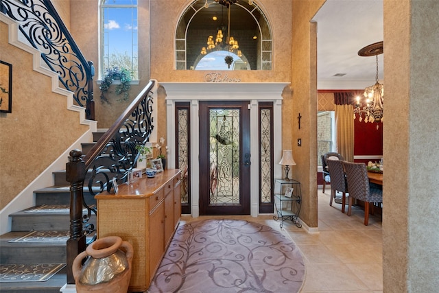 tiled entryway featuring an inviting chandelier, a high ceiling, stairway, and ornamental molding