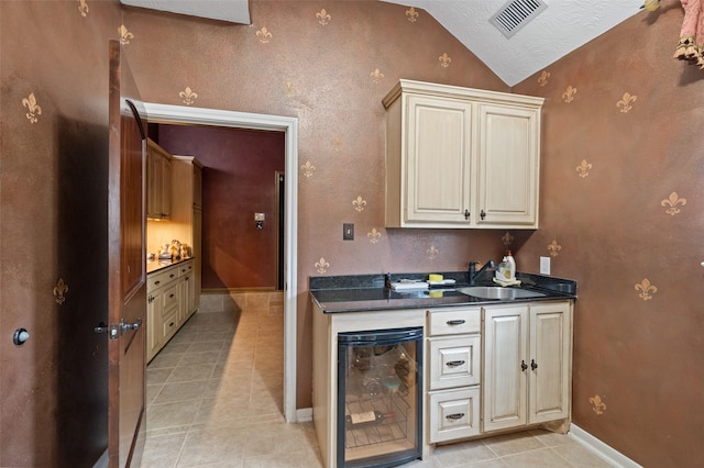 kitchen with wine cooler, a sink, lofted ceiling, and dark countertops