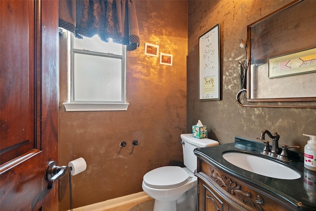 half bath featuring baseboards, vanity, and toilet