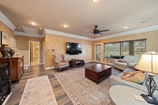 living area with attic access, visible vents, crown molding, and wood finished floors