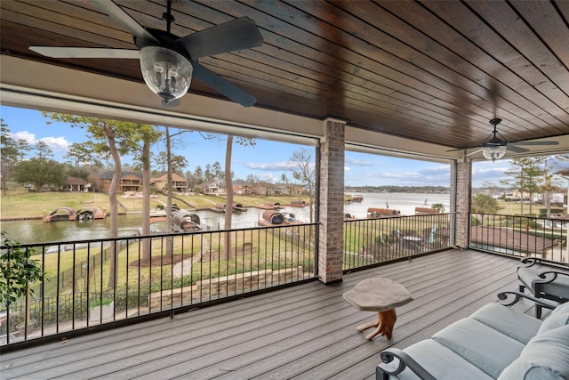 wooden terrace with a water view and ceiling fan