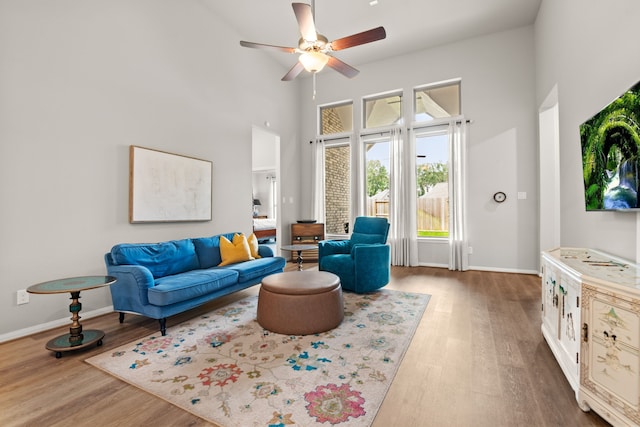 living room featuring wood finished floors, a towering ceiling, and baseboards