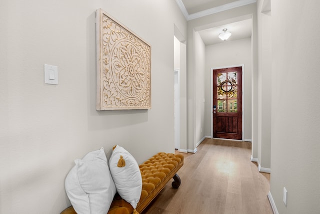 doorway to outside featuring light wood-type flooring, baseboards, and crown molding