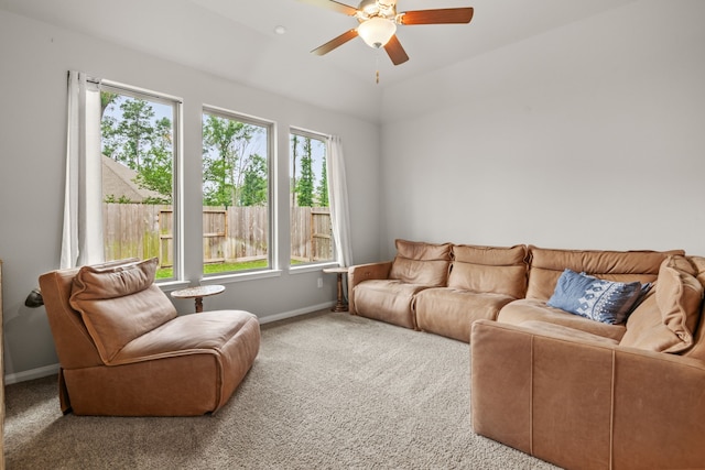 living area featuring carpet floors, baseboards, and a ceiling fan