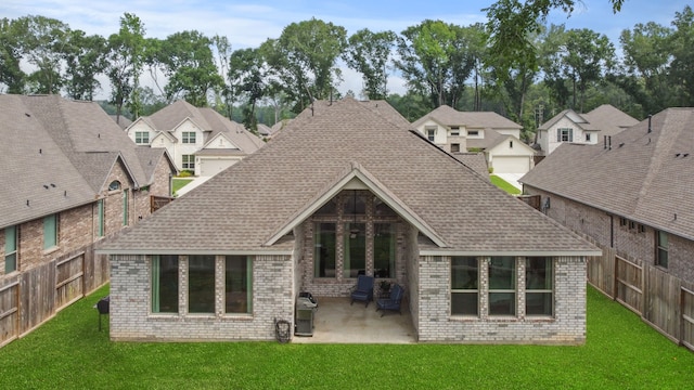 back of house with a patio area, roof with shingles, a yard, and brick siding